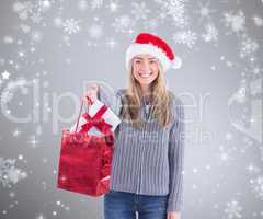 Composite image of festive blonde holding christmas gift and bag