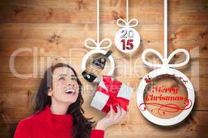 Composite image of happy brunette in red jumper hat showing a gi