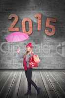 Composite image of festive blonde holding umbrella and bags