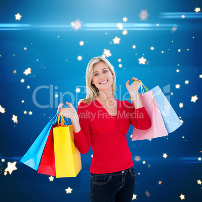 Composite image of happy blonde holding shopping bags