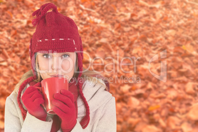 Composite image of happy blonde in winter clothes holding mug