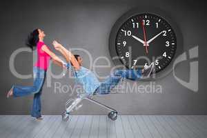 Composite image of young couple having fun with shopping cart
