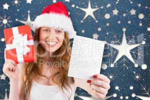 Composite image of festive redhead holding a gift