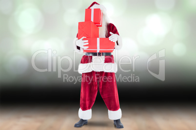 Composite image of santa covers his face with presents