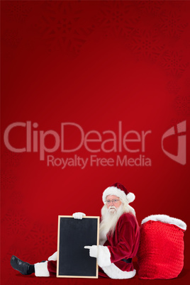 Composite image of santa sits leaned on his bag with a board