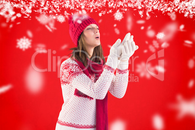 Composite image of woman in warm clothing blowing over hands