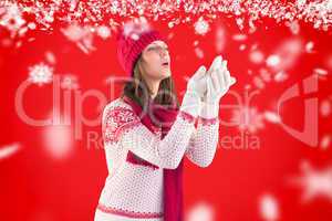 Composite image of woman in warm clothing blowing over hands