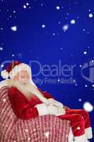 Composite image of smiling santa relaxing on the armchair