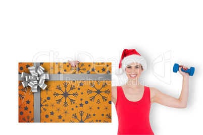 Composite image of festive fit brunette holding gift card and du