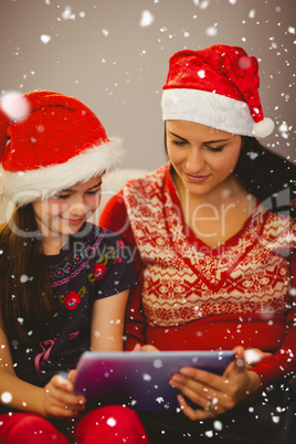 Composite image of festive mother and daughter using tablet