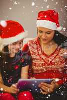 Composite image of festive mother and daughter using tablet