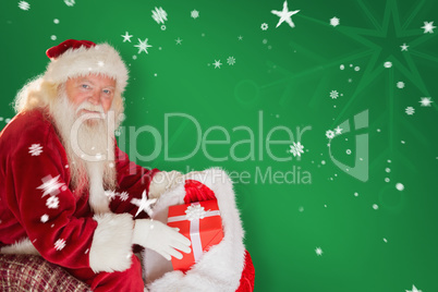 Composite image of father christmas taking red gift in his bag