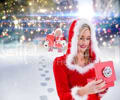 Composite image of festive blonde opening a gift