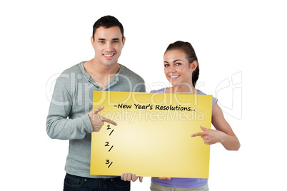 Composite image of smiling young couple pointing at sign they ar