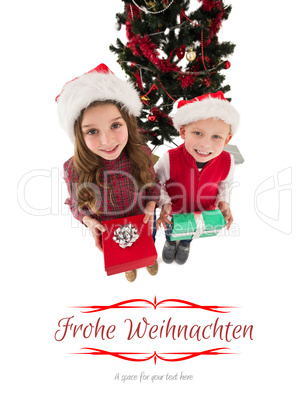 Composite image of festive little siblings smiling at camera hol
