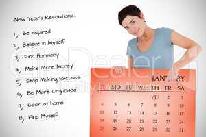 Composite image of smiling woman pointing at calendar on a panel