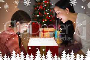 Composite image of festive mother and daughter opening a glowing
