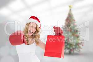 Composite image of festive blonde with boxing gloves and shoppin