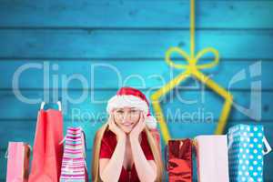 Composite image of festive blonde smiling at camera with gift ba