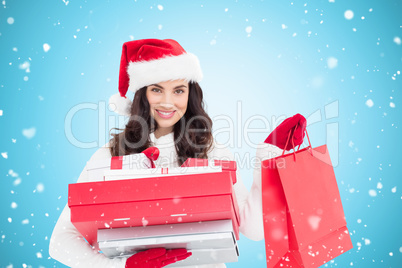 Composite image of festive brunette holding christmas gifts and