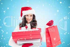 Composite image of festive brunette holding christmas gifts and