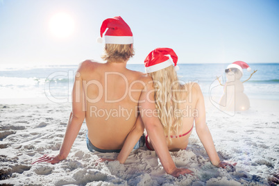 Composite image of rear view of couple sitting on beach