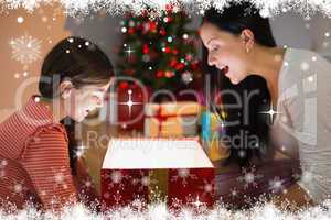 Composite image of festive mother and daughter opening a glowing