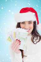 Composite image of festive brunette holding her cash