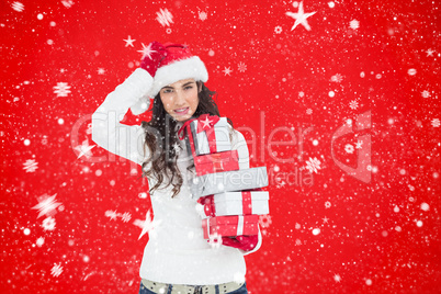 Composite image of stressed brunnette in santa hat holding gifts