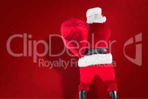 Composite image of rear view of santa holding a sack