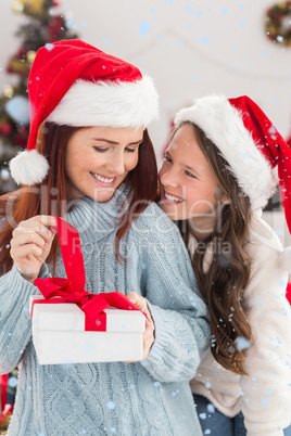 Composite image of festive mother and daughter on the couch with gift