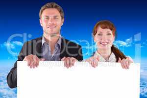 Composite image of smiling couple holding large sign