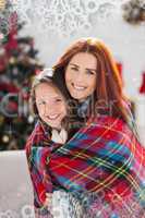 Composite image of festive mother and daughter wrapped in blanket