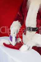 Composite image of father christmas is ironing his hat