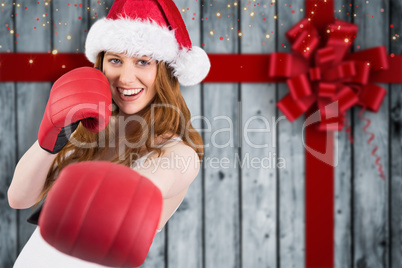 Composite image of festive redhead punching with boxing gloves