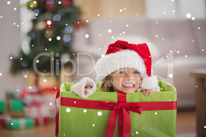 Composite image of cute little girl sitting in giant christmas g