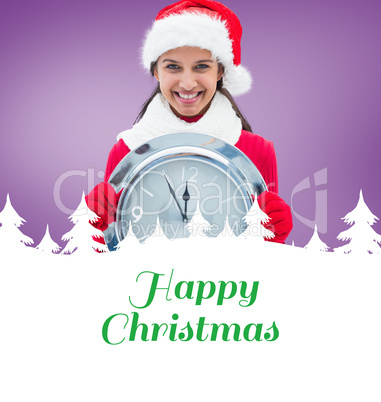 Composite image of festive brunette holding clock