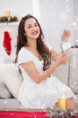 Composite image of happy brunette holding heart for decoration