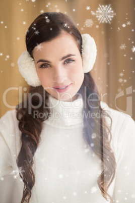 Composite image of pretty brunette with ear muffs smiling at camera