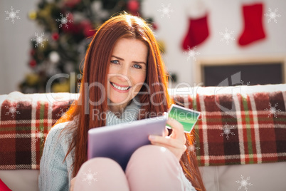 Composite image of festive redhead shopping online with tablet