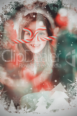 Composite image of happy little girl in santa hat holding candy