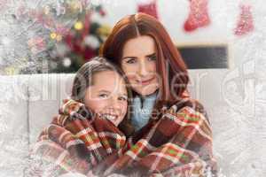 Composite image of festive mother and daughter wrapped in blanke