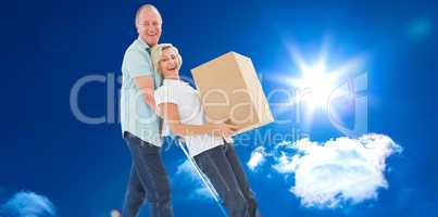 Composite image of fun older couple holding moving boxes