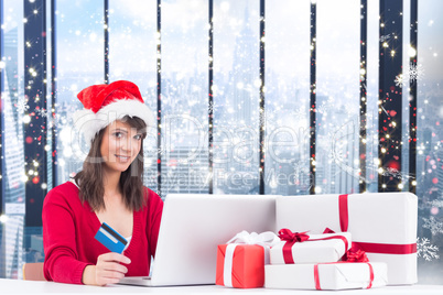 Composite image of festive brunette shopping online with laptop