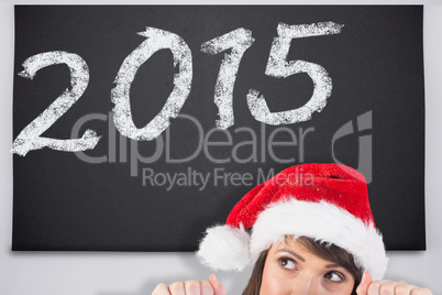 Composite image of festive brunette holding a poster while looki