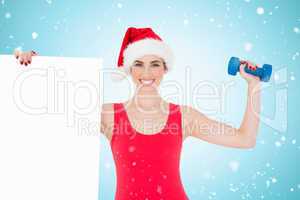 Composite image of festive fit brunette holding page and dumbbel