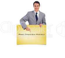 Composite image of goodlooking man holding and pointing at a big