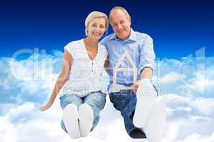 Composite image of happy mature couple holding a house shape