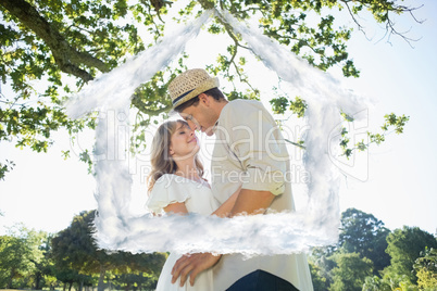 Composite image of cute couple standing in the park embracing