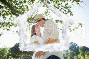 Composite image of cute couple standing in the park embracing